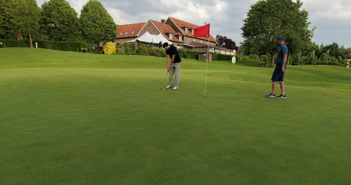 Zwei Golfer auf dem Grün vor dem Clubhaus